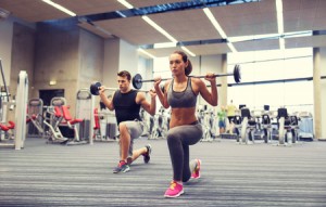 51808619 - young man and woman with barbell flexing muscles and making shoulder press lunge in gym